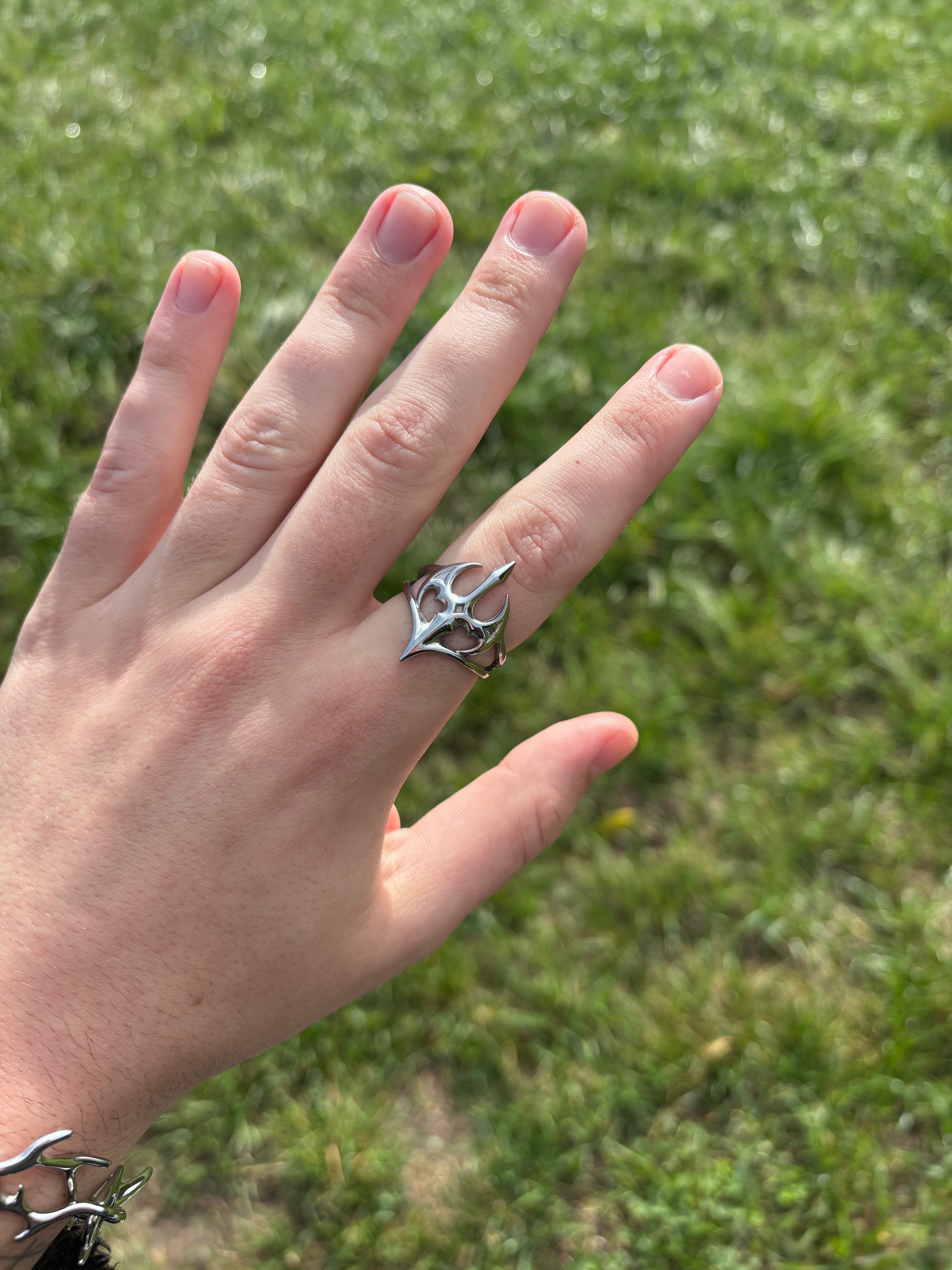 Nightshade Ring aus 316L-Edelstahl an der Hand getragen, durchbrochenes Schwert- und Flügelmotiv