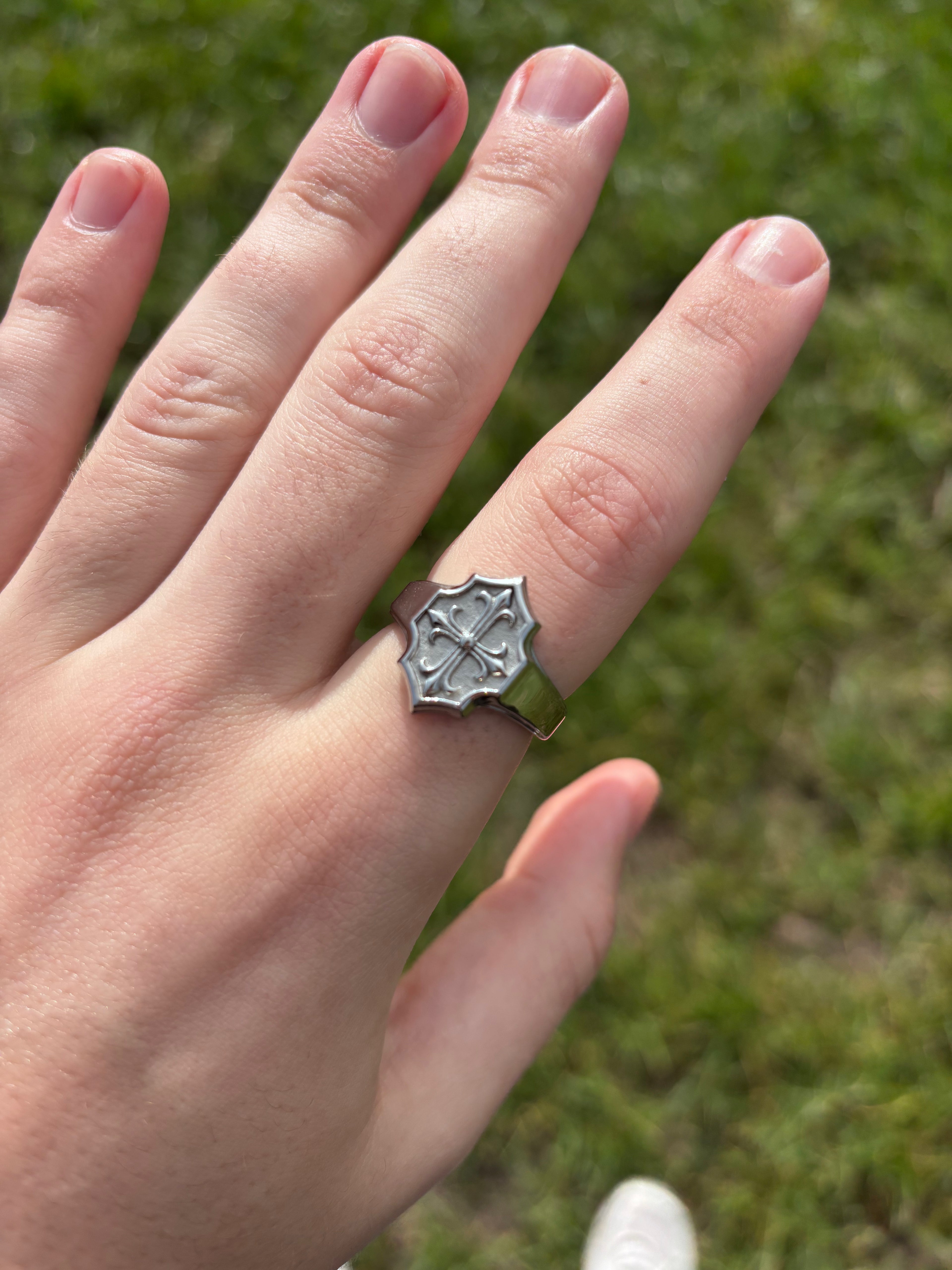 Lily Cross Ring aus 316L-Edelstahl am Finger, Detailaufnahme bei Tageslicht