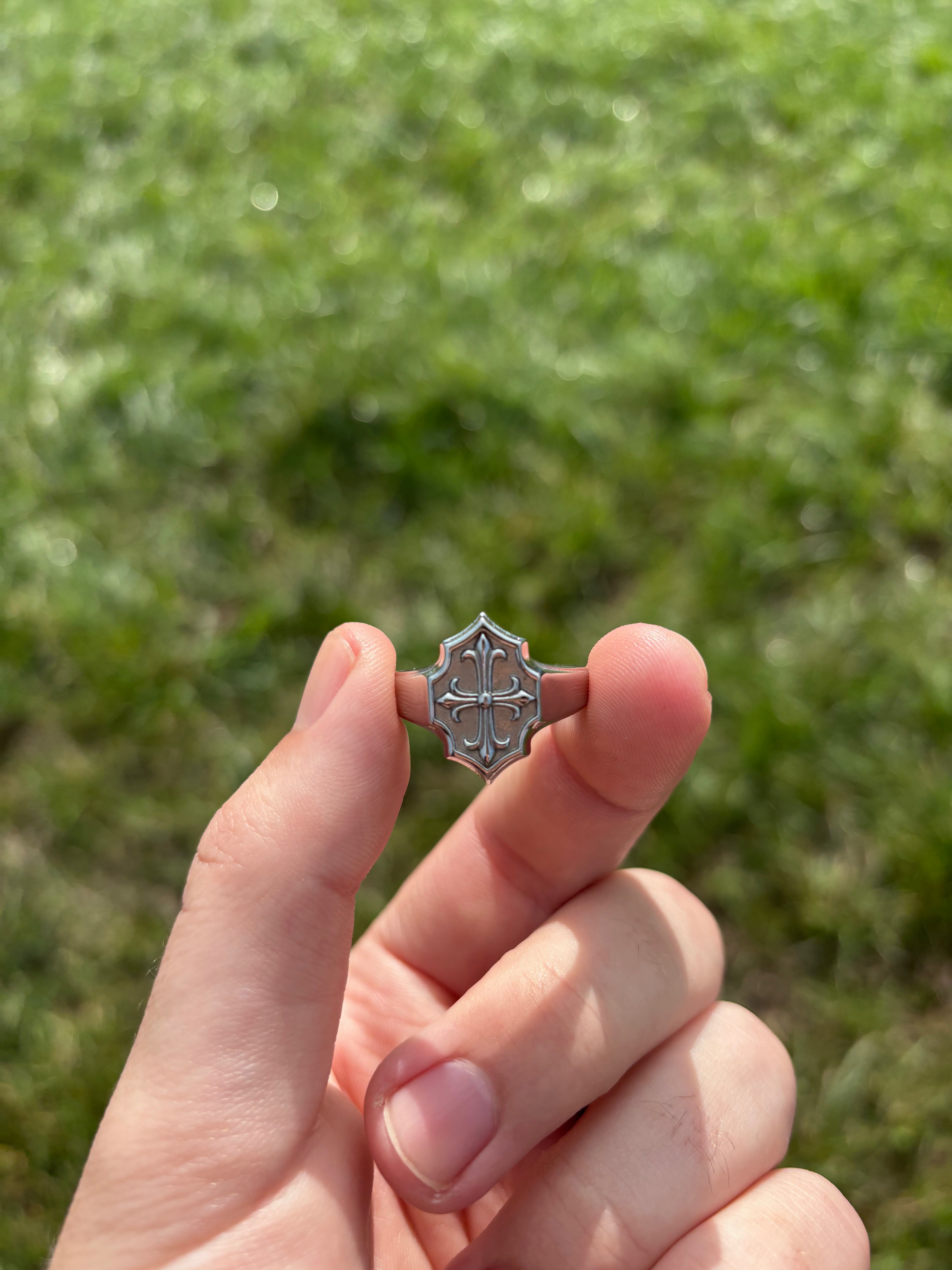Lily Cross Ring aus 316L-Edelstahl in der Hand, Lilien-Kreuz-Relief im Licht
